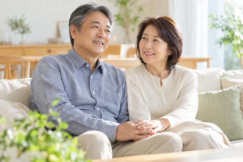 並んで座り、ほっとした表情で手を重ねる夫婦