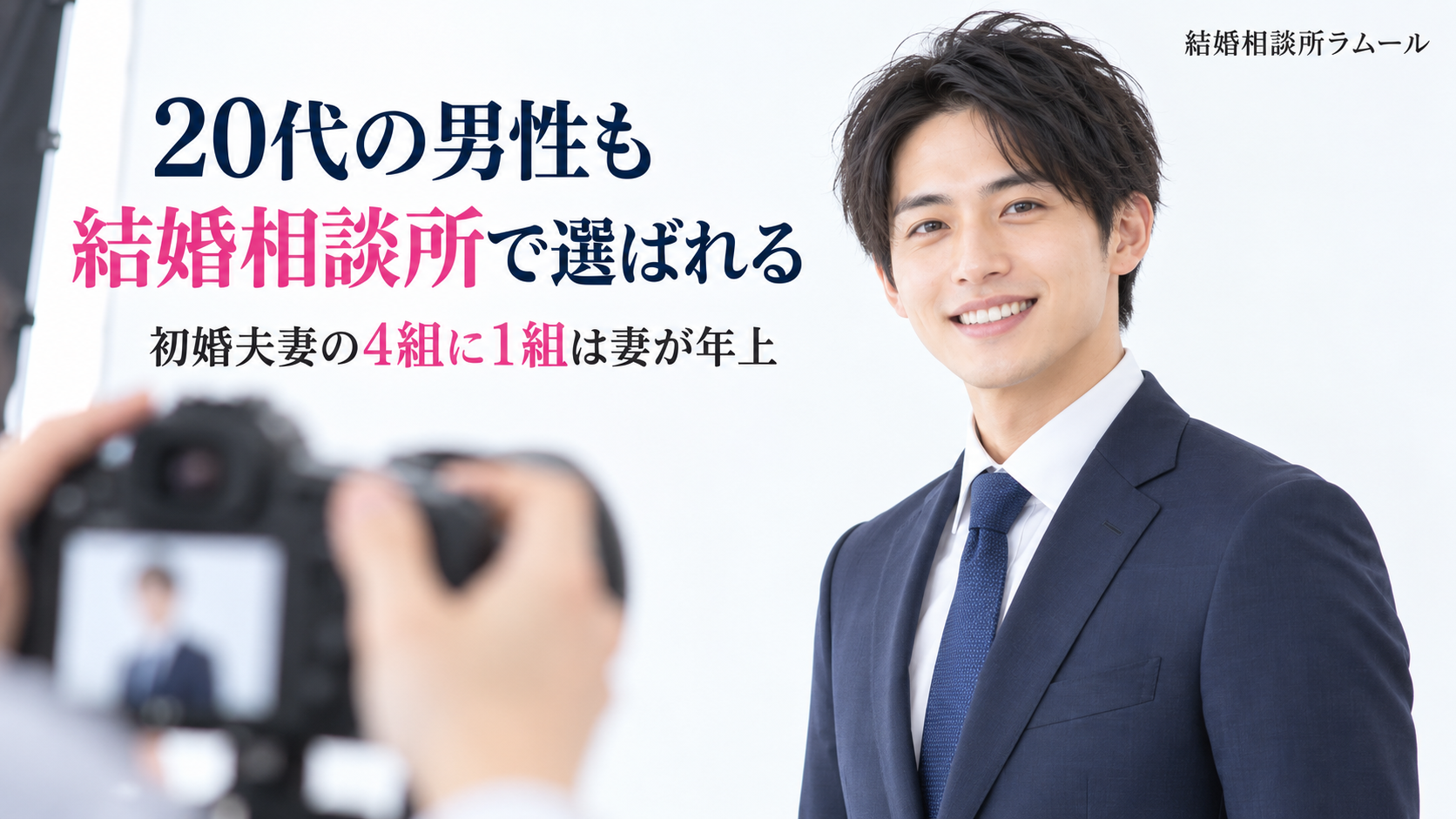 写真スタジオでプロフィール写真を撮ってもらい自然に笑うスーツ姿の28歳の男性（20代の男性も結婚相談所で選ばれる・初婚夫妻の4組に1組は妻が年上）