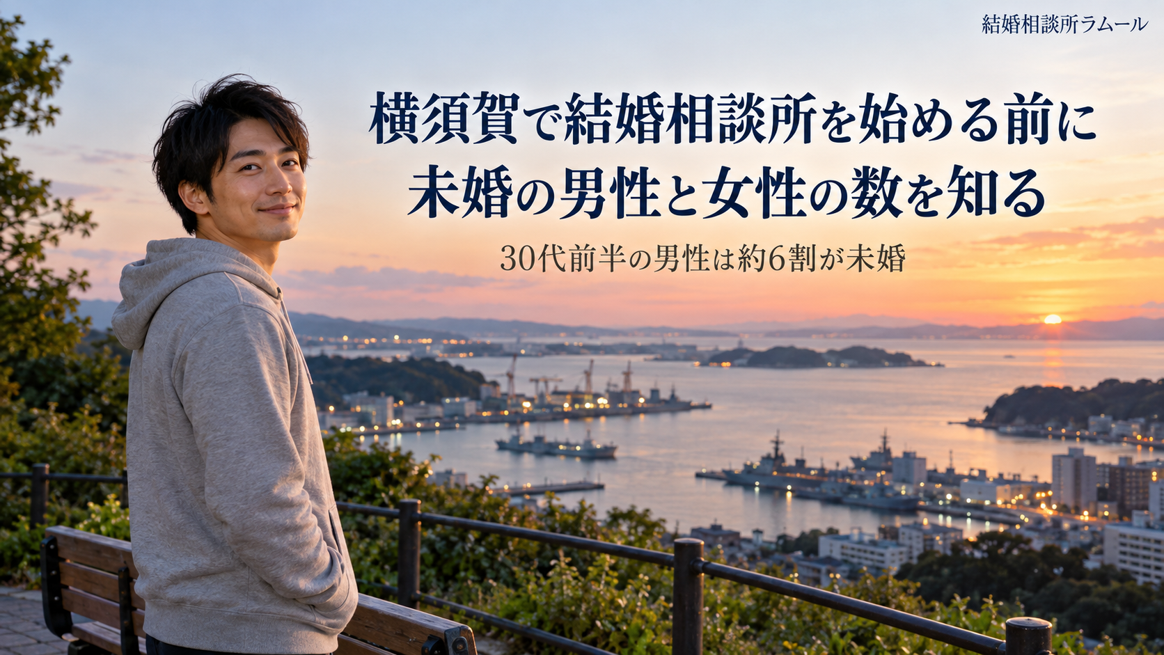 夕方の横須賀の港を見下ろす丘の上の公園で景色を眺めて微笑むグレーのパーカーの33歳の男性(横須賀で結婚相談所を始める前に未婚の男性と女性の数を知る・30代前半の男性は約6割が未婚)